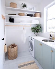 a washer and dryer in a white laundry room with open shelving on the wall