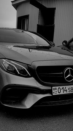 black and white photograph of a mercedes benz sports car parked in front of a building