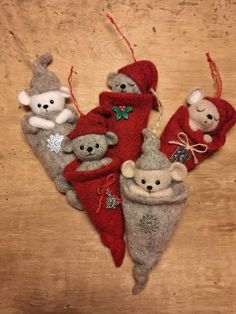 three stuffed animals hanging from christmas decorations on a wooden table with red and white stockings