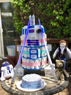 a cake made to look like a r2d2 tower with baby items around it