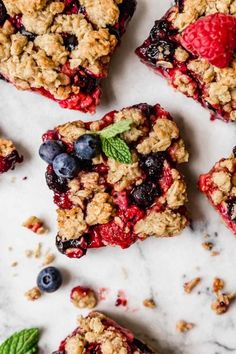 blueberry crumbles with fresh berries and mint leaves on a white marble surface