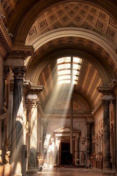 the sun shines through an arched window into a building with columns and statues in it