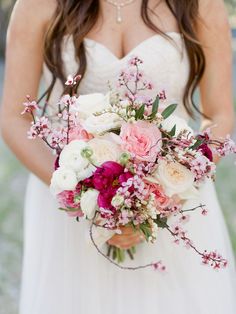 a bride holding a bouquet of pink and white flowers on her wedding day at the park