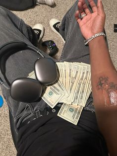 a man is sitting on the floor with money and headphones