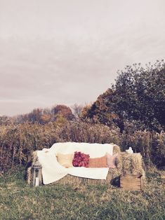 a couch sitting on top of a lush green field next to a pile of hay