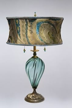 a lamp that is sitting on top of a table next to a light fixture with a blue and gold shade