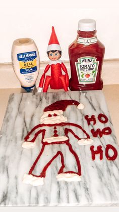 an elf is sitting next to some condiments on a marble counter top, with a bottle of ketchup in the background