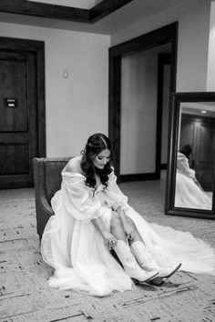 a woman sitting on top of a chair in front of a mirror wearing cowboy boots