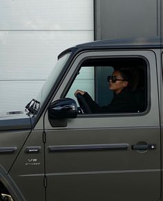 a woman sitting in the driver's seat of a gray truck with her hand on the steering wheel