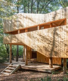 a wooden structure in the woods with stairs leading up to it's upper level