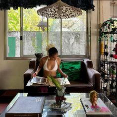 a woman sitting on a couch in front of a window with an umbrella over her head