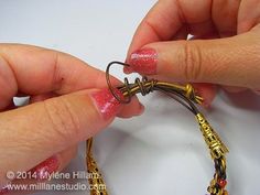 two hands are working on some gold and pink bracelets with metal wire attached to them