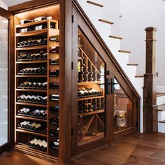 a wine cellar in the corner of a room with stairs leading up to an upper level