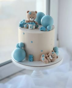 a white cake with blue decorations and teddy bears