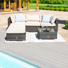 a couch and table sitting on top of a wooden deck next to a swimming pool