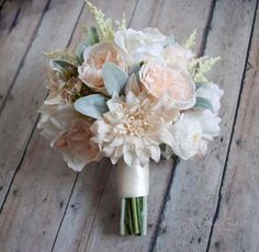 a bridal bouquet with pink flowers and greenery on the side of a wooden floor