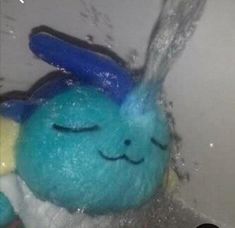 a blue stuffed animal is in the water with its eyes closed and it's head covered