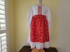 This is an adorable girls costume dress inspired by a Croatian traditional dress. This cute dress is made with white broadcloth.  The bodice and sleeves are trimmed with red ribbon that features tiny white flowers.  The skirt  is trimmed with red embroidered eyelet lace.    It has a red floral apron that ties in the back with grosgrain ribbon.    The apron is attached so you don't need to worry about losing it.   Perfect for International days at school, heritage days, Christmas around the World programs, Halloween, or just for fun!    This dress is new and unworn, just like the pictures. All the seams and edges are serged and it closes with hook and loop in the back. Available in sizes 2 thru 8.  ALSO NOTE: The skirt can be made with different colors.  Just add a note. International Days, Tiny White Flowers, Floral Apron, Traditional Outfit, Eastern European, Folk Costume, Traditional Dress, Eyelet Lace, Costume Dress