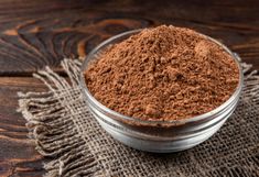 a bowl filled with cocoa powder on top of a wooden table next to a cloth