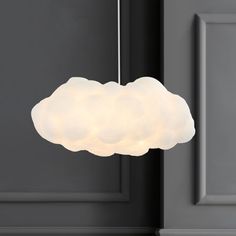 a white cloud shaped light hanging from a ceiling fixture in a dark room with gray walls