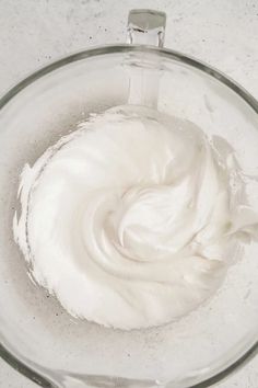 a glass bowl filled with whipped cream on top of a counter