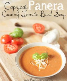 a bowl of creamy tomato basil soup on a cutting board