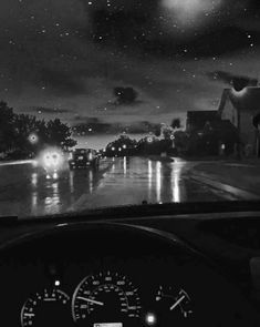 the dashboard of a car on a rainy night with cars driving down the road in front of it