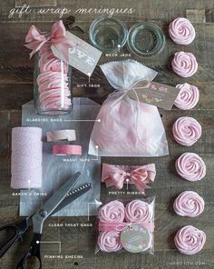 pink cupcakes and other items are arranged on a wooden table with labels, ribbons, and scissors