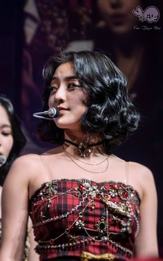 a woman in a red and black dress singing into a microphone