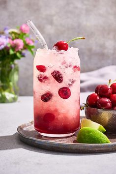 a drink with cherries and limes on a tray next to some other fruit