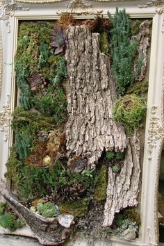 an old frame is covered with moss and other plants in the shape of a tree trunk