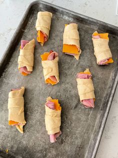 several pieces of food wrapped in paper on a baking sheet, ready to go into the oven