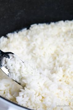 the spoon is full of white rice in a pot