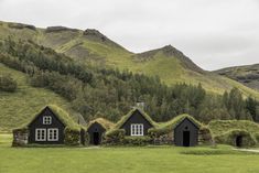 three black houses with grass roofs in the mountains