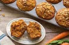 carrot muffins on a plate next to fresh carrots and other food items