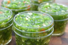 several jars filled with green vegetables on top of a wooden table