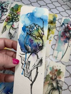 a person holding up some watercolor paper with flowers on it