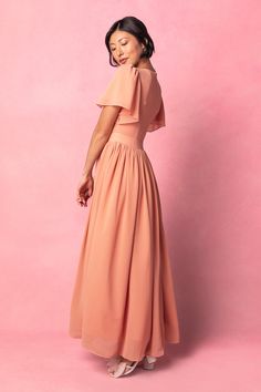 a woman in a pink dress is standing against a pink background with her eyes closed