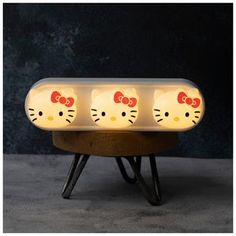 three hello kitty lamps sitting on top of a wooden stand with lights in the shape of cats