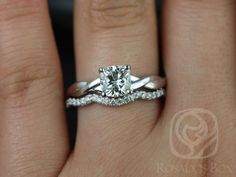 a woman's hand with a diamond ring on top of her wedding band and an engagement ring in the middle