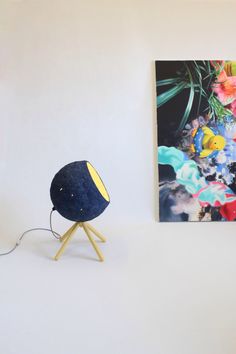 a blue ball sitting on top of a wooden stand next to a painting