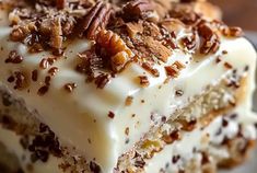 a piece of cake with white frosting and pecans on top