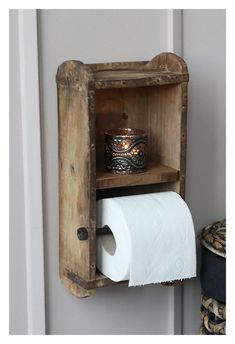 an old wooden box with a roll of toilet paper in it is hanging on the wall