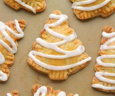 several pastries with icing sitting on top of a baking sheet in the shape of a christmas tree