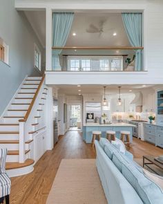 a living room filled with furniture and a stair case in front of a kitchen area