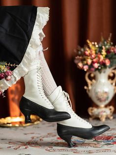 a pair of black and white high heeled shoes sitting on top of a table