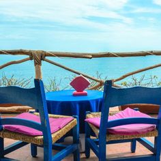 three chairs and a table on a balcony overlooking the ocean