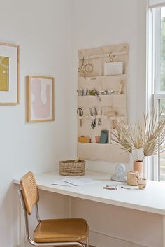 a white desk with a chair, potted plant and pictures on the wall behind it