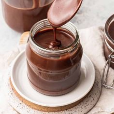 a spoon is pouring chocolate into a jar