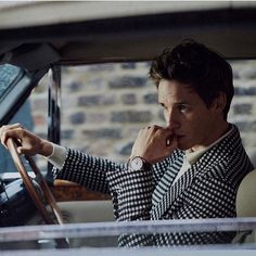 a man sitting in the driver's seat of a car with his hand on his chin